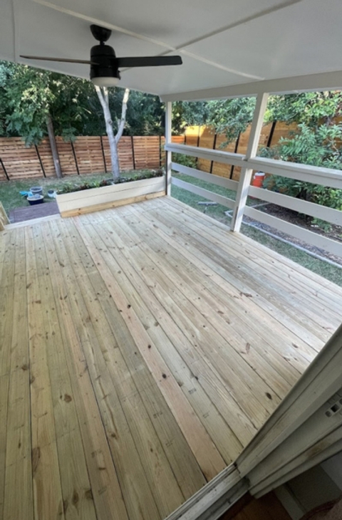 A patio deck with light wood and white horizontal safety fencing