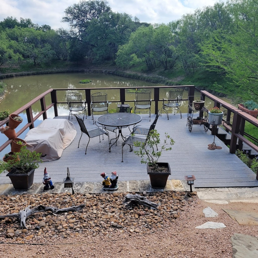 Patio deck overlooking a pond with decorations, table, and chairs
