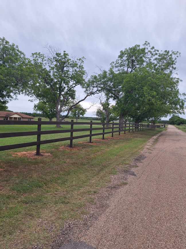 Dark, horizontal, ranch-style wood fence with trees